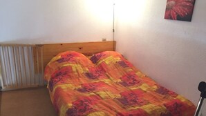 A single bed with a wooden headboard in a room with white walls and a radiator.
