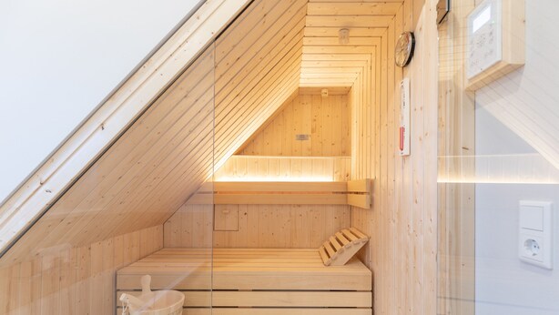 A sauna with wooden benches and a wooden bucket.