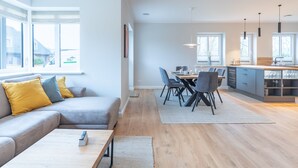 A modern living room with a sofa, coffee table, and dining area with chairs and a table.