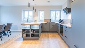 A modern kitchen with grey cabinets, a wooden countertop, and a built-in wine rack.