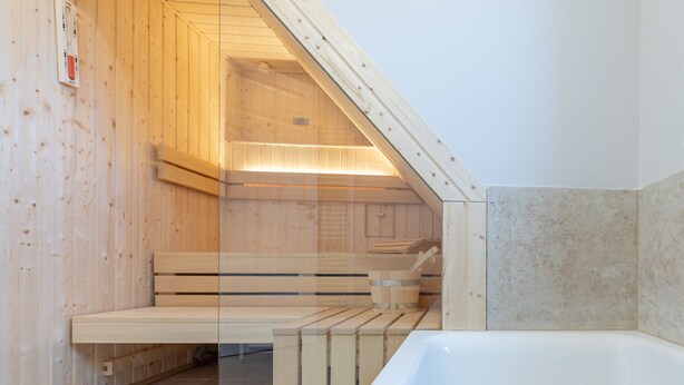 Ein Saunaraum mit Holzbänken und einer weißen Badewanne.