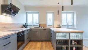 Eine moderne Küche mit einer Holzausziehtheke, einem Einbauofen und einem Weinkühlschrank.