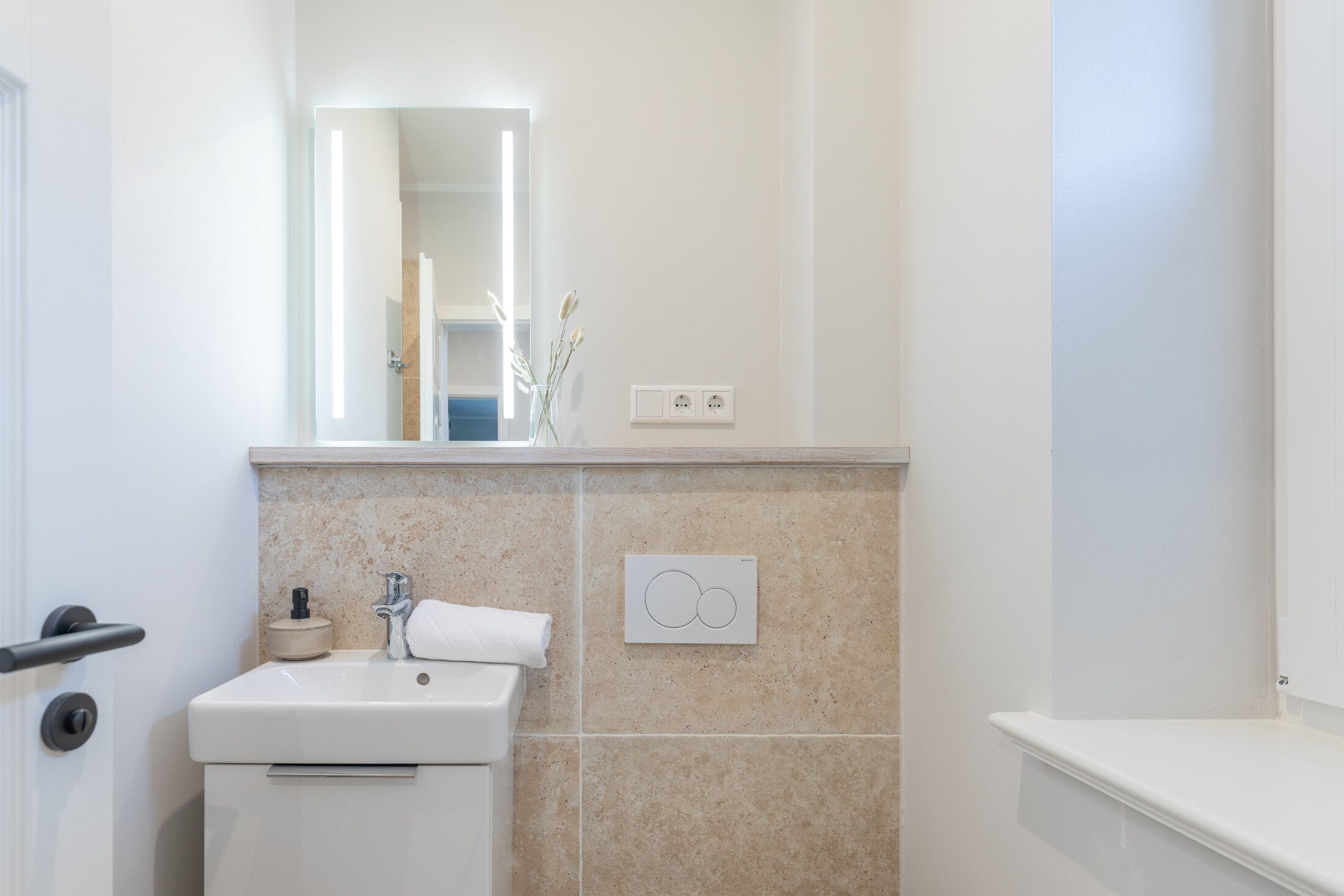 A bathroom with a white sink, a mirror, and a towel rack.