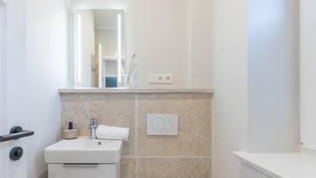 A bathroom with a white sink, a mirror, and a towel rack.