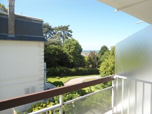 Un balcone con vista libera su un giardino curato e, sullo sfondo, il mare.