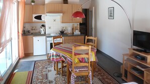Une cuisine compacte avec des meubles en bois, un four à micro-ondes et un luminaire suspendu rouge.
