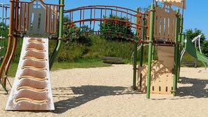 A playground with a slide, climbing structures, and a sand area.