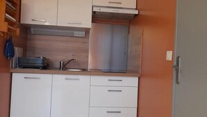 A compact kitchen with white cabinets, a stainless steel sink, and a built-in oven.