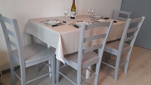A dining table with a polka dot tablecloth, four grey chairs, and a bottle of wine.
