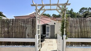 Ein verschlossenes Tor mit einer Pergola, einer überdachten Terrasse und einem Weg, der zu einem Gebäude führt.