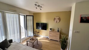 Ein modernes Wohnzimmer mit einer Couch, einem Couchtisch, einem Fernseher und einem Holzschrank.