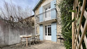Un patio con un muro de piedra, una mesa de madera con sillas y una puerta azul.