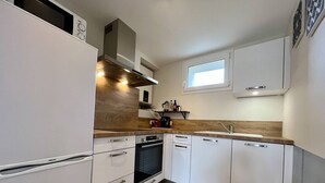 Una cocina moderna con armarios blancos, encimera de madera, horno empotrado y una ventana sobre el fregadero.