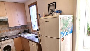 Ett kompakt kök med tvättmaskin, spis, diskho och kylskåp.