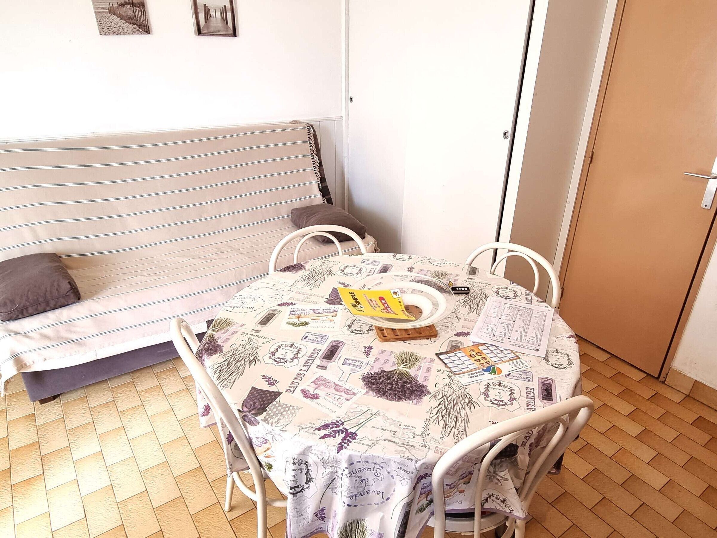Una habitación pequeña y acogedora con un sofá, una mesa con mantel de flores y una puerta.