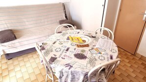 Ett litet, ombonat rum med en soffa, ett bord med ett blommigt bordsduk och en dörr.