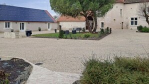A courtyard with a large tree, a building with a tiled roof, and a solar panel on the left.