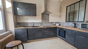 A modern kitchen with dark cabinets, a stainless steel range hood, a microwave, and a built-in oven.