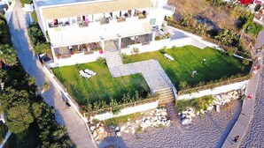 Un edificio moderno con un patio, mobiliario exterior y zona de piscina.