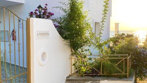 Un edificio blanco con un cartel que dice 'NTERIDES', una reja de metal y una escalera que lleva a un balcón con vistas al mar.