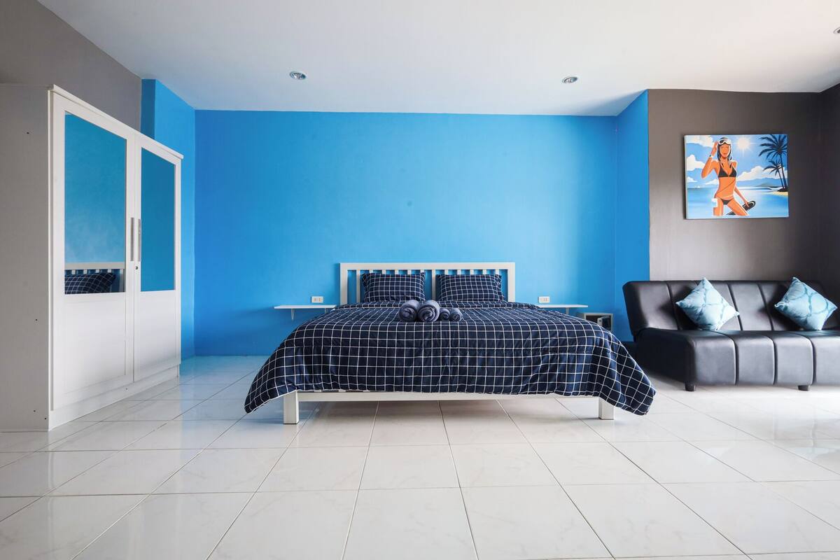 A bedroom with a bed, a wardrobe, a nightstand, and a painting on the wall.