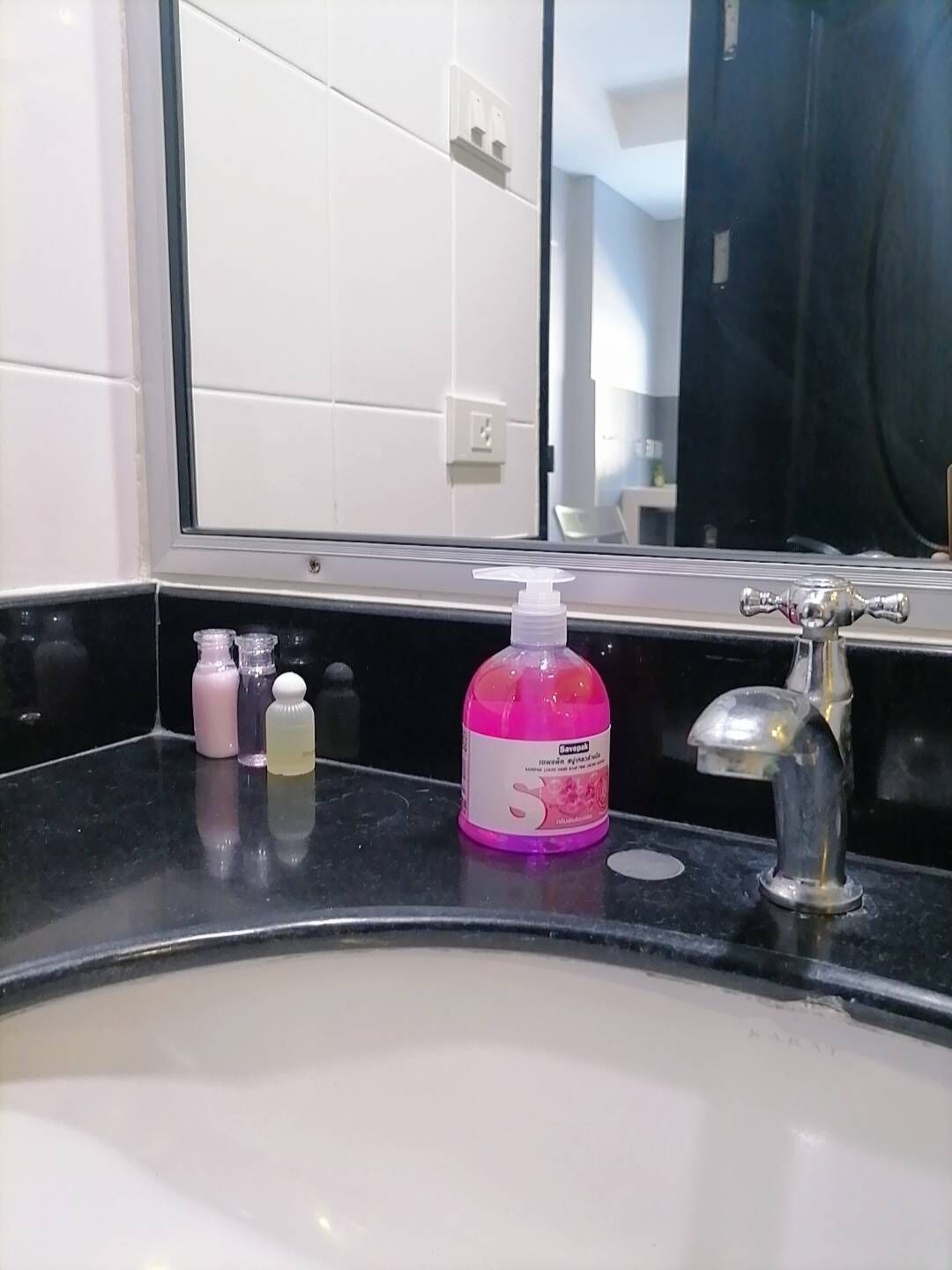 A bathroom with a sink, mirror, and toiletries.