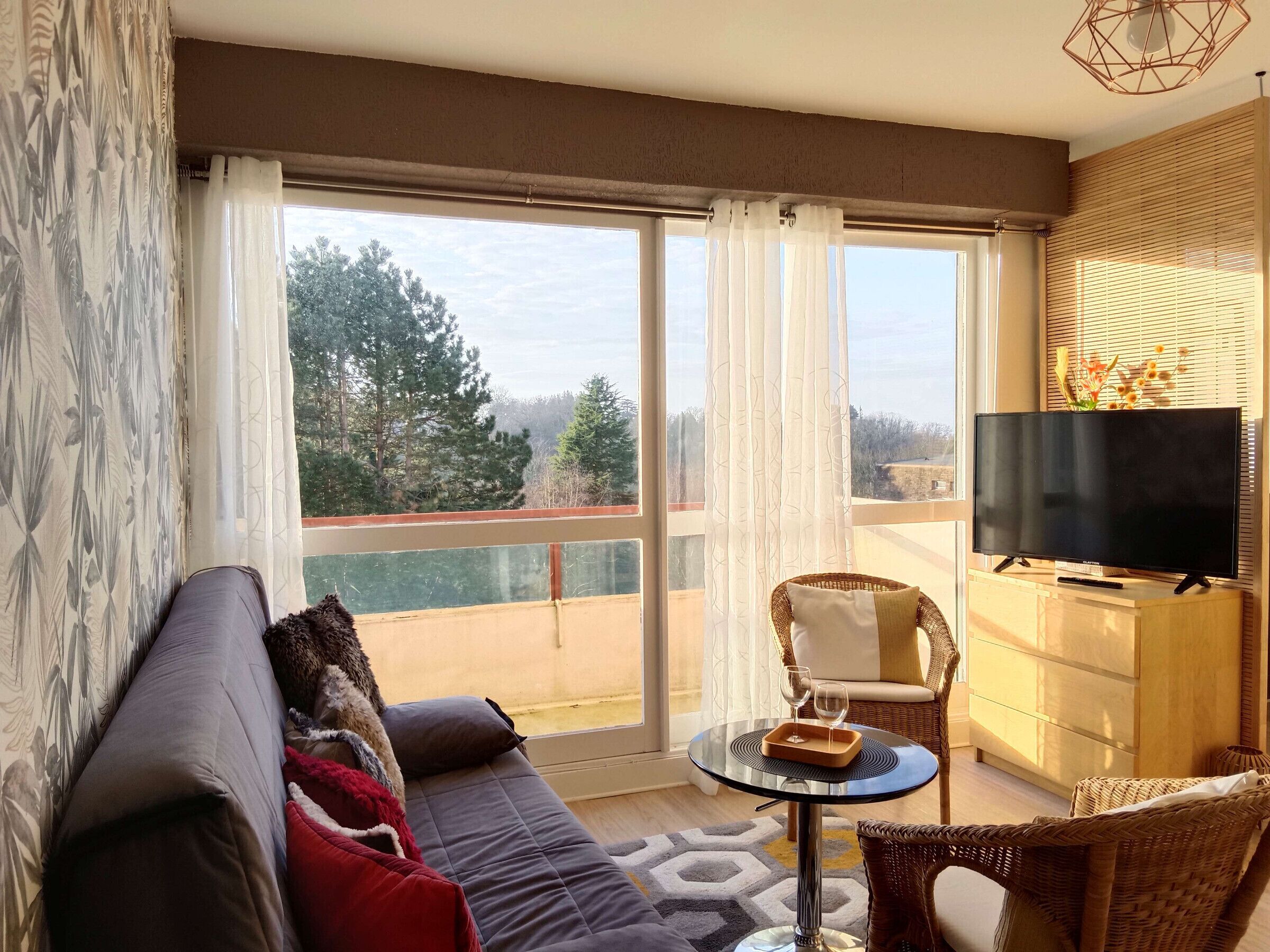 Una sala de estar moderna con un sofá, una mesita redonda y un televisor sobre un mueble.