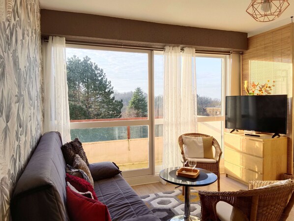 A modern living room with a sofa, a small round table, and a television on a stand.
