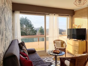 A modern living room with a sofa, a small round table, and a television on a stand.