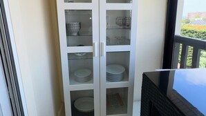 Eine weiße, gläserne Vitrine mit mehreren Einlegeböden, gefüllt mit Geschirr und Gläsern.