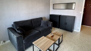 Ein modernes Wohnzimmer mit einem dunkelgrauen Sofa, einem Holztisch und schwarzen Schränken.
