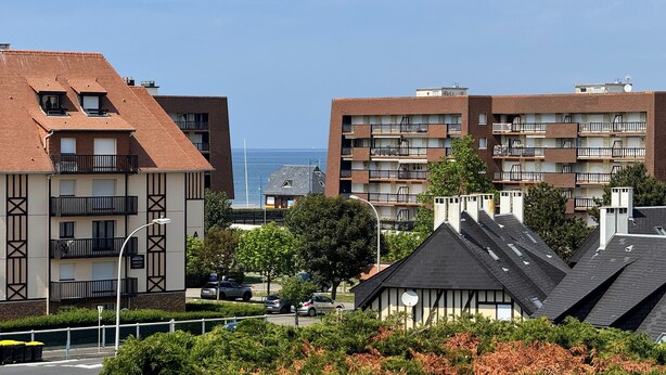 Ein Wohngebäude mit mehreren Balkonen, freiem Blick auf das Meer und einer Mischung aus moderner und traditioneller Architektur.