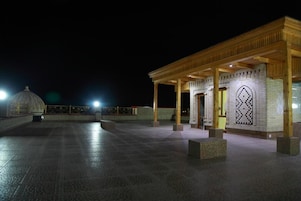A covered outdoor area with a tiled floor and a wooden pavilion structure.