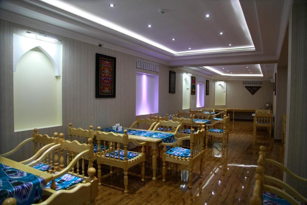 A hotel dining area with wooden tables and chairs, a long corridor, and framed artwork on the walls.