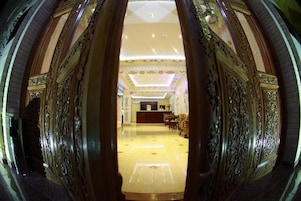 A grand lobby with ornate gold detailing, a reception desk, and a spacious seating area.