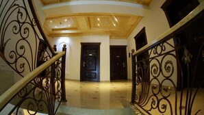 A grand staircase with ornate metal railings leading to a dark wooden door. - Hotel Sultan Boutique (Samarkand)