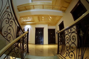 A grand staircase with ornate metal railings leading to a dark wooden door.
