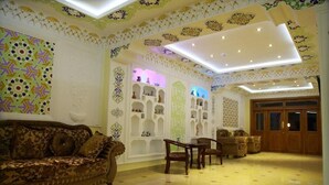 A room with a patterned wall, a sofa, a wooden cabinet, and a door. - Hotel Sultan Boutique (Samarkand)