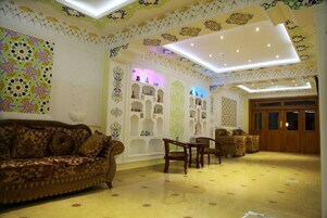A room with a patterned wall, a sofa, a wooden cabinet, and a door.