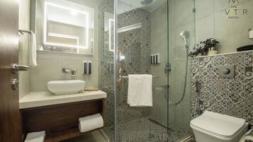 Un baño moderno con ducha de vidrio, lavamanos blanco y retrete.