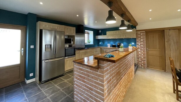A modern kitchen with a central island, stainless steel appliances, and a brick accent wall.