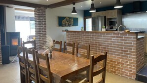 A modern kitchen with a brick island, wooden dining table, and chairs.