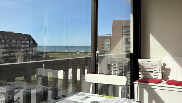 Ein Balkon mit Blick aufs Meer, ein Tisch mit Zeitungen und eine Reihe weißer Plastikstühle.