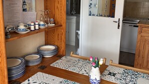 Eine Küche mit Holzböden, einem Esstisch mit gemusterten Tischdecken und einer Vase mit Blumen.
