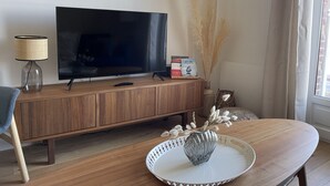 Een moderne woonkamer met een houten tv-meubel, een flatscreen televisie, een lamp, een vaas met pluimen en een dienblad met een glazen vaas.