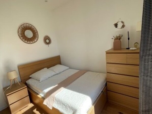 Ein Schlafzimmer mit einem Holzbett, einem Nachttisch, einer Kommode und zwei Wandbildern.