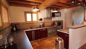 A modern kitchen with wooden beams, stainless steel appliances, and a central island.