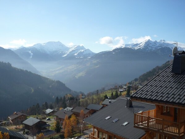 A mountain lodge with a view of snow-capped peaks and a valley below.