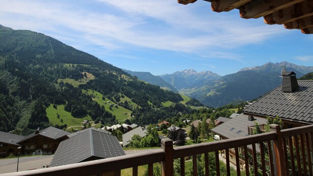 A wooden balcony overlooking a mountainous landscape with a village below.