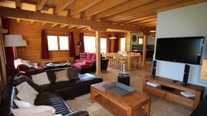 A cozy log cabin interior with a living room, dining area, and kitchen.